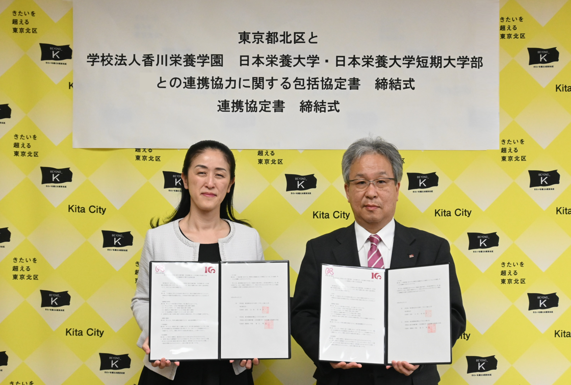 協定書を手にする山田 加奈子 北区長と香川明夫 学長